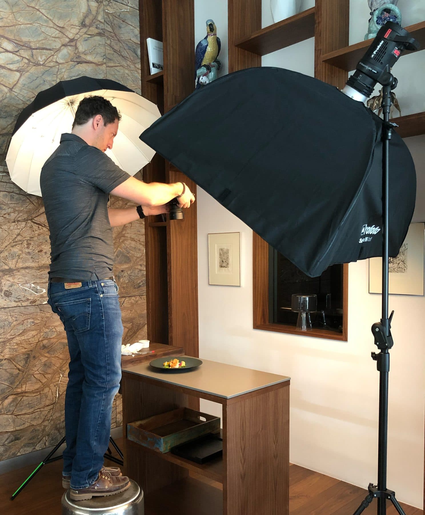 Marc Conzelmann at a product shoot — lining up a plated dish on the table under an umbrella and a softbox; the photographer whose everyday work gave rise to VAULO