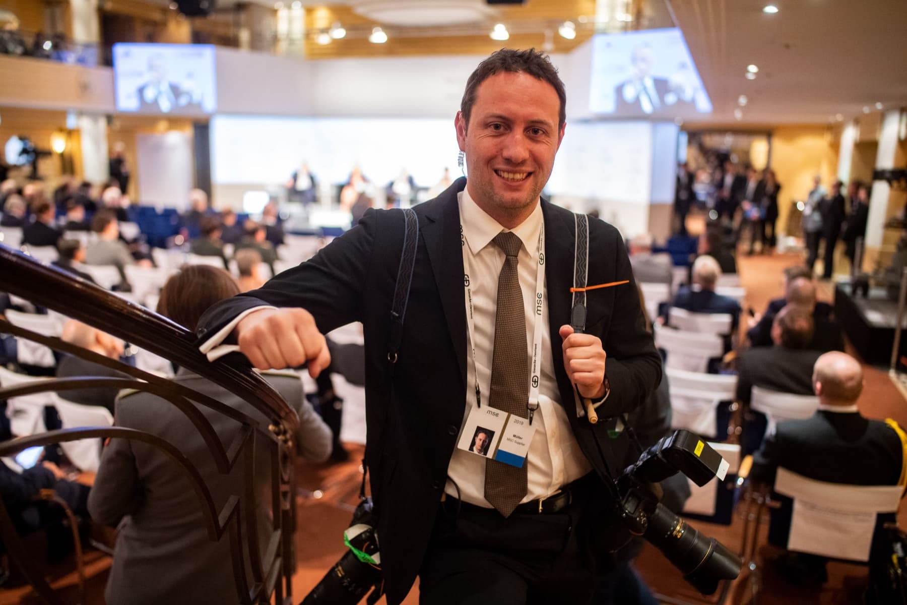 Marc Conzelmann with two cameras in the conference hall of the Munich Security Conference — working as a photographer