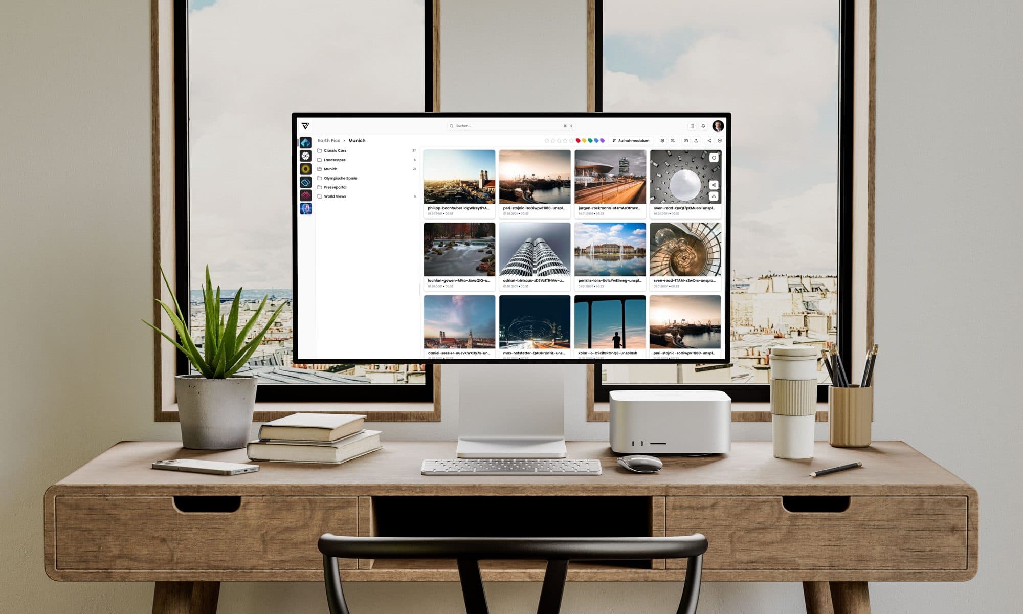 VAULO on a monitor in an office — the "Munich" folder view with image tiles, the folder tree on the left, search at the top