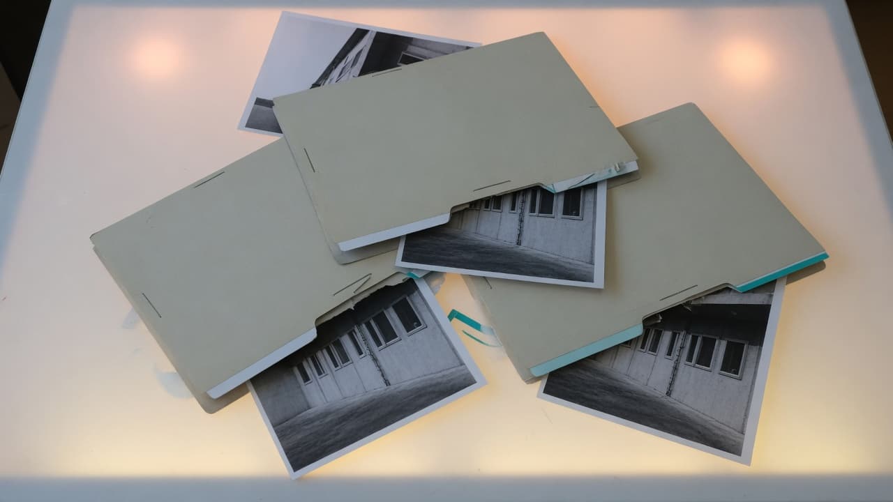 Four folders holding the same architectural prints, stacked messily on a light table